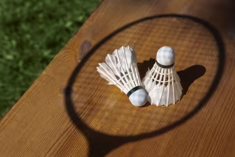 Badminton bolde på bordet, med skygge af badmintonketchen henover
